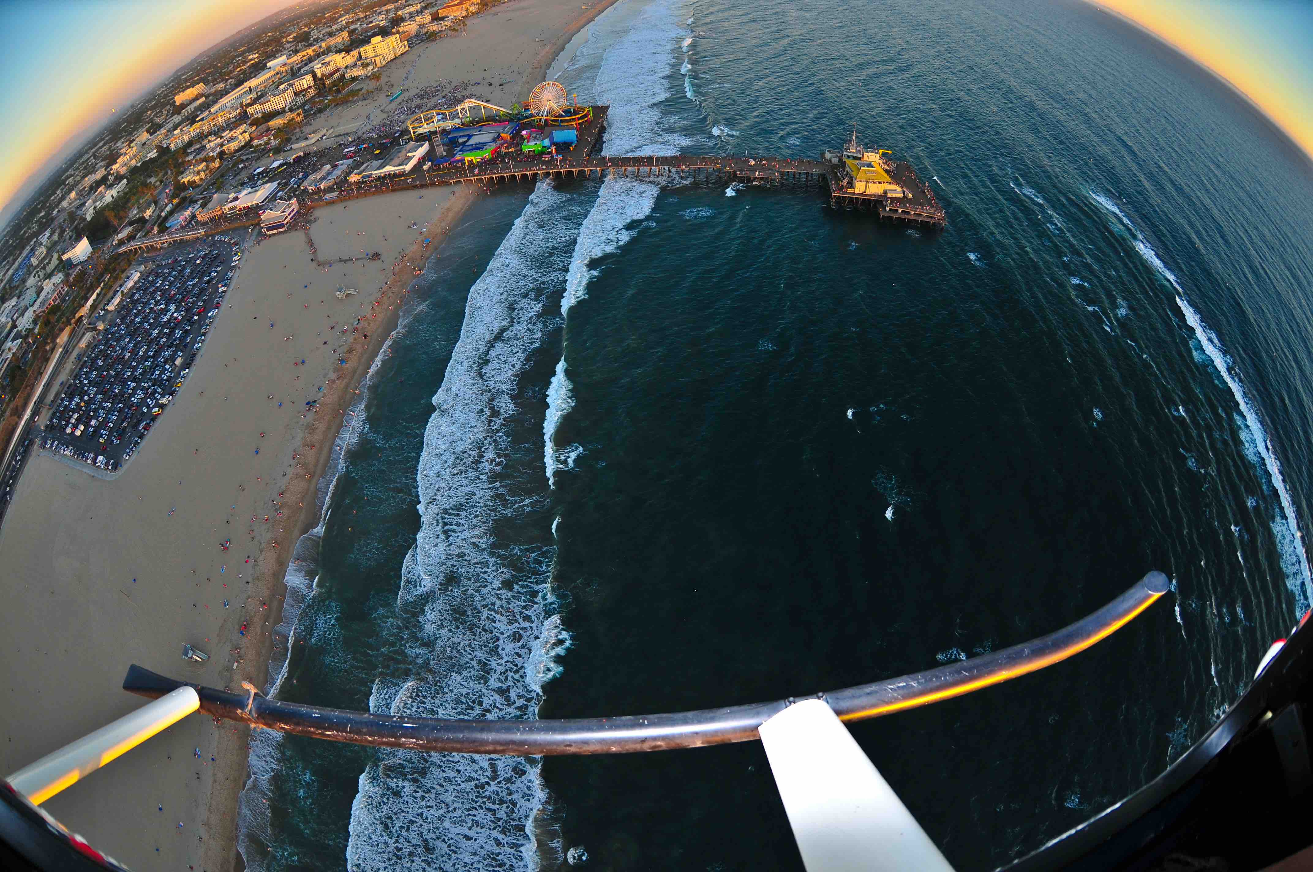 Helicopter flight above Santa Monica, California at sunset. Taking photos of the ocean and the Santa Monica Pier.