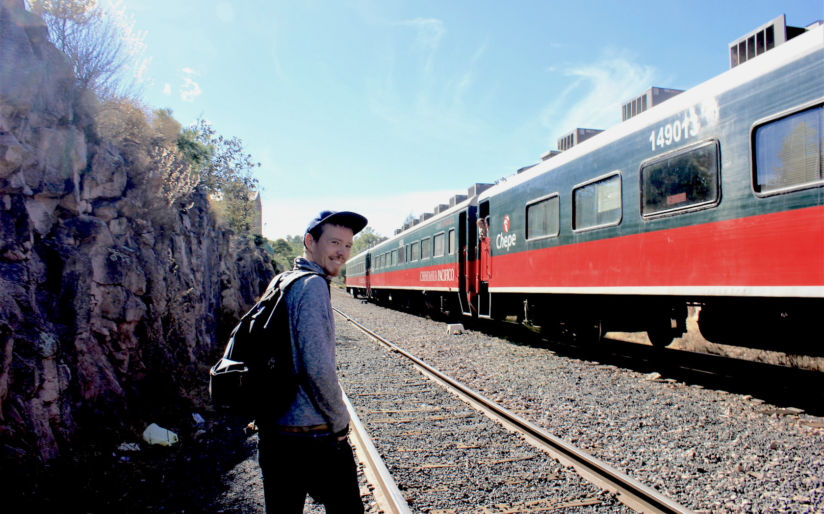A young man walks beside the El Chepe train in Mexico.