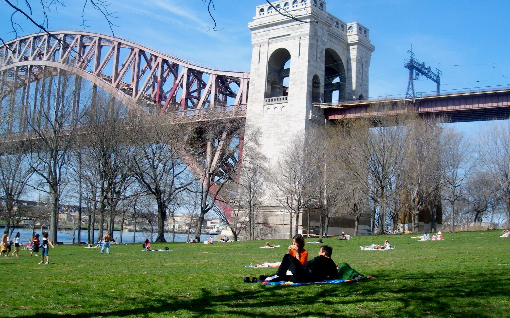 People relax with a picnic near suspension bridge in Astoria, New York City.
