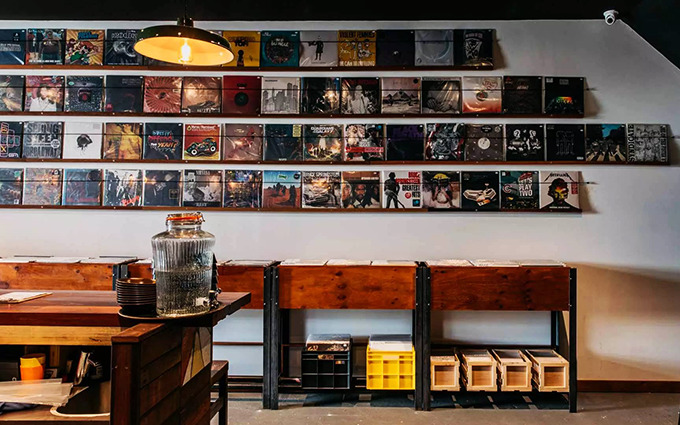 Interior of the bar Cottonmouth Records, featuring a wall of mounted records and the corner of a bar countertop.