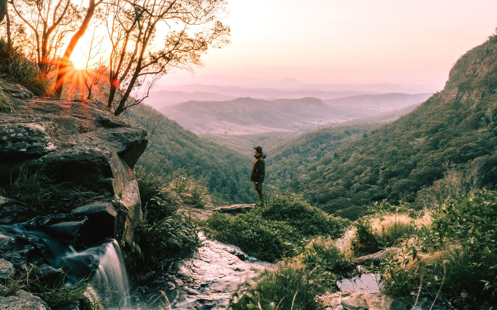 Man standing in Moran Falls at dusk looking out to view