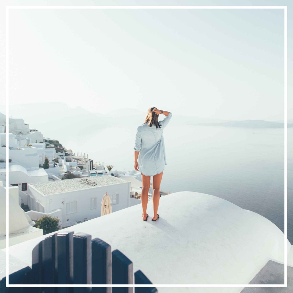 Woman standing on top of a roof in Santorini, an island in Greece
